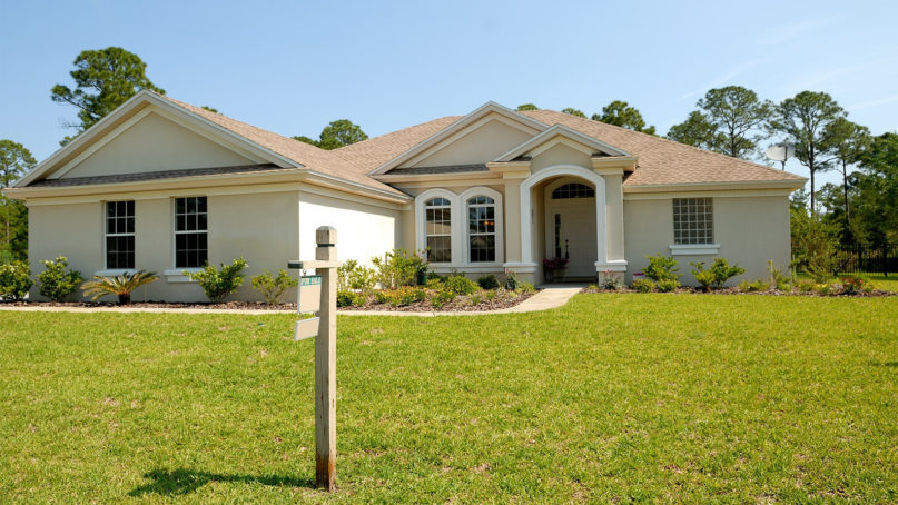 cream and white bungalow with for sale sign in front yard