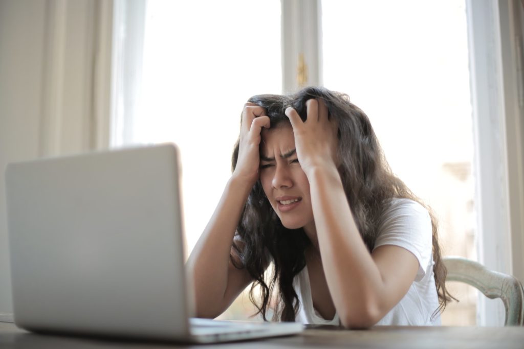 frustrated woman holding head and staring at laptop